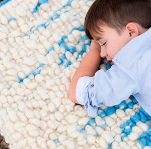 Niño acostado sobre tapiz artesanal de lana merina y lino,
